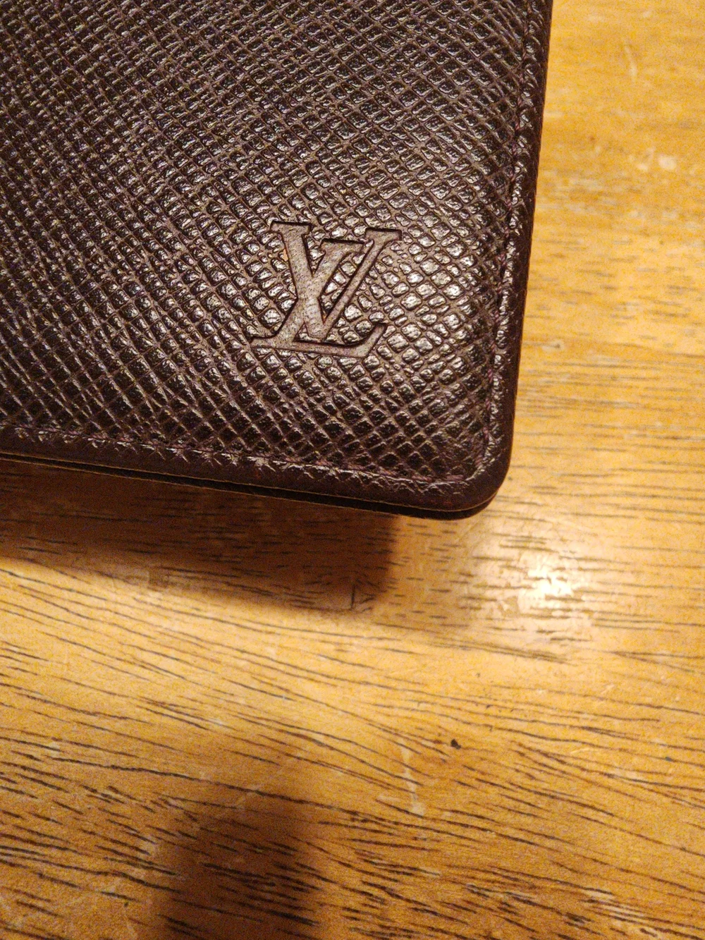 burgandy Louis Vuitton Taiga leather bifold wallet featuring a debossed LV